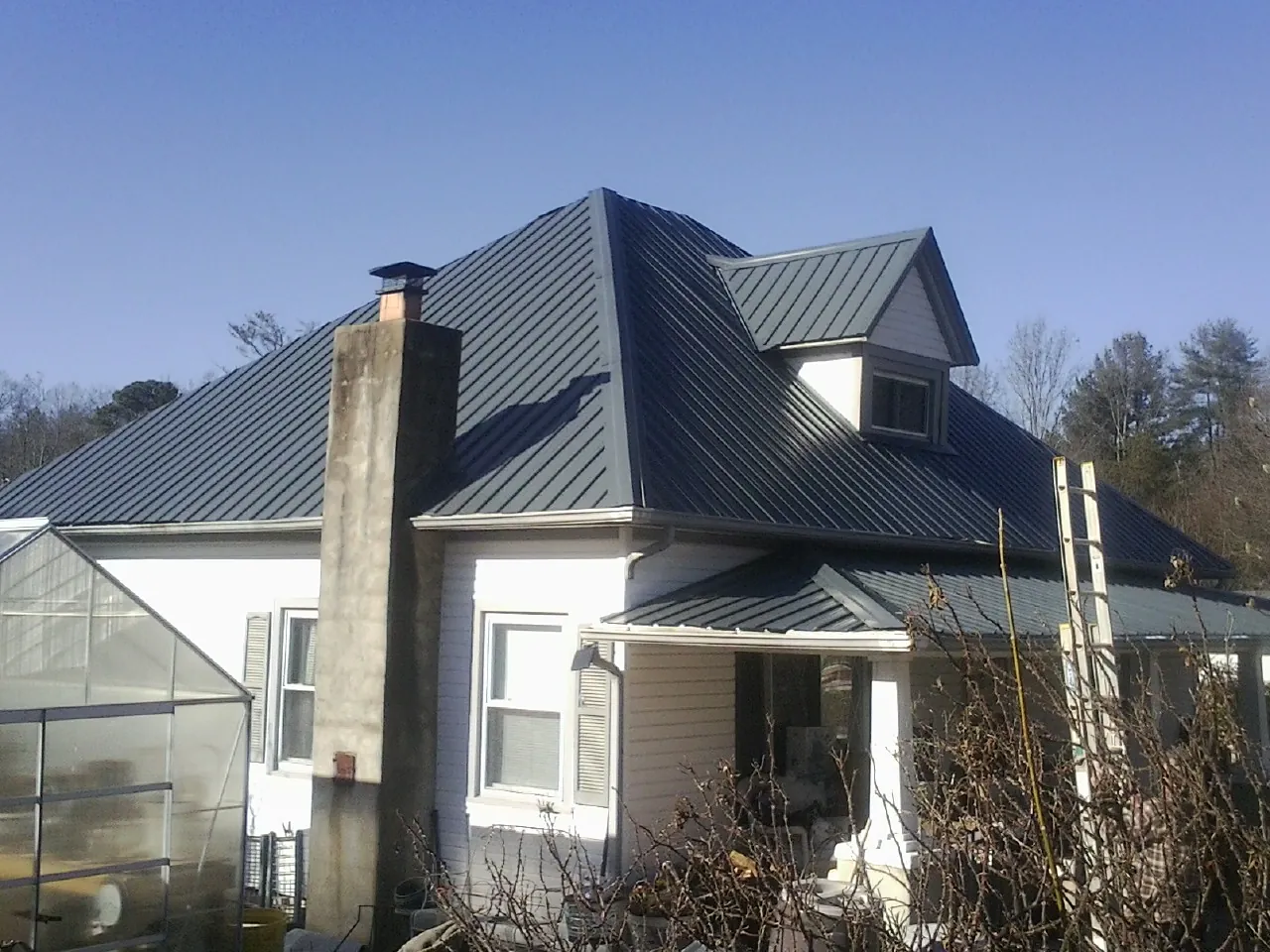 Dark blue standing seam metal roof on a white farmhouse with dormer — Slate & Tile Roof Repair by Roofing Brothers in Yellville