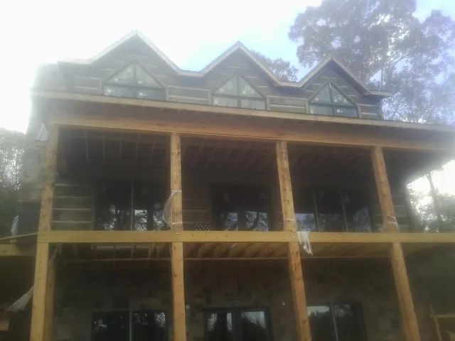 Dormers and porch framing on a large log home under construction — Roof Coating work by our crew in Yellville