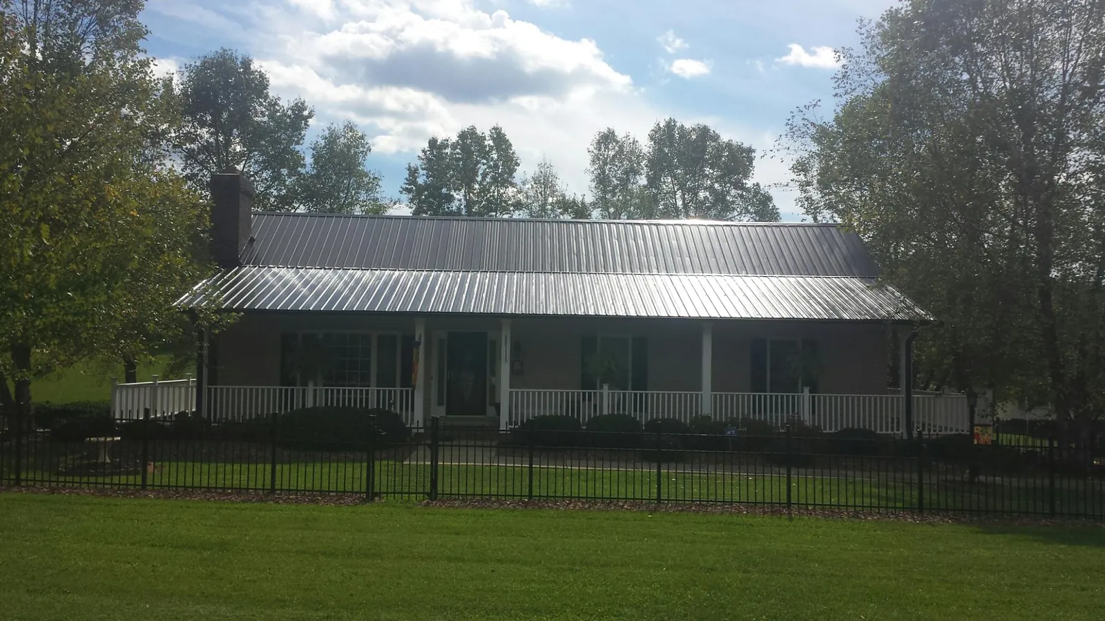 Gray metal roof on a brick ranch with a full width front porch — Gutter Guard Installation work by our crew in Yellville