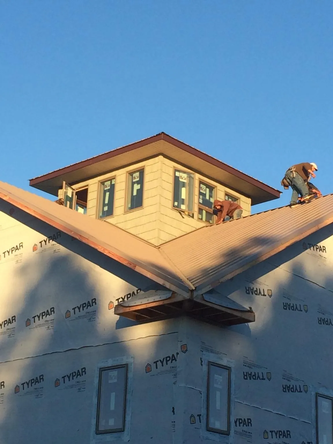 Roofers working around a rooftop cupola on a new metal roof at sunset — Roof Waterproofing in Yellville by Roofing Brothers
